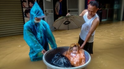 A boy sits in a floating basket as people wade through a flooded street following the impact of Typhoon Yagi, in Hanoi, Vietnam, September 11, 2024. (REUTERS)