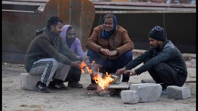 Labourers sit around the bonfire to keep themselves warm on a cold winter day in Ludhiana on Wednesday. (Manish/HT)