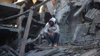 A Palestinian man sits on the rubble of a destroyed building in the Nuseirat refugee in the central Gaza Strip on December 13, 2024, amid the continuing war between Israel and Hamas. (AFP/Eyad Baba)