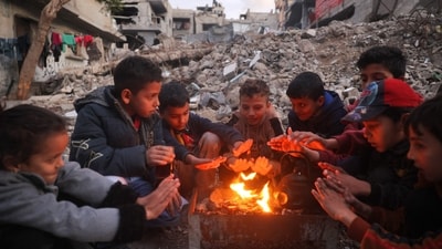 Children warm by the fire at the Bureij camp for displaced Palestinians on December 30, 2024, amid the continuing war between Israel and Hamas.&nbsp; (AFP/Eyad Baba)