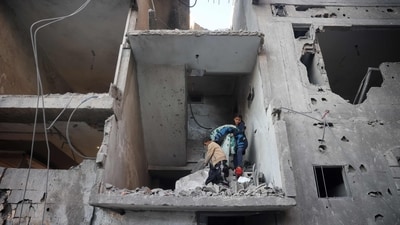 Palestinian children salvage belongings in front of a building destroyed in an Israeli airstrike in Nuseirat in the central Gaza Strip on December 1, 2024. (AFP/Eyad Baba)