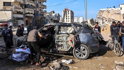 People inspect the remains of a civilian vehicle that was hit by Israeli bombardment along Jalaa Street in central Gaza City on December 22, 2024. (AFP/Omar Al-Qattaa)