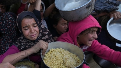 Palestinian girls struggle to reach for food at a distribution center in Khan Younis, Gaza Strip Dec. 6, 2024. (AP/Abdel Kareem Hana)