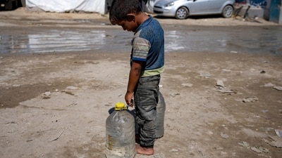 A displaced child carries filled water bottles at a makeshift tent camp in Deir al-Balah, Gaza, Aug. 29, 2024. (AP/Abdel Kareem Hana)