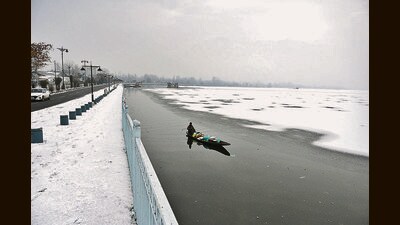 A man rows his boat on a frozen Dal Lake after light snowfall in Srinagar on Thursday. (Waseem Andrabi/HT)