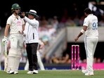 Umpire Sharfuddoula Ibne Shahid Saikat (C) gestures as he stands between Australia's Sam Konstas (L) and India's captain Jasprit Bumrah (R).
