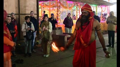 Foreign tourists watch a saint of Agni Akhada performing arti of the Akhada deity in his camp ahead of Mahakumbh-2025 in Prayagraj. (HT Photo)