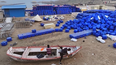 Workers repair a boat next to a pile of interlocking plastic cubes meant for building a floating jetty on the Ganges river in preparation for the upcoming Maha Kumbh Mela. (AP)