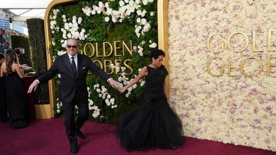David Zayas, left, and Liza Colon-Zayas arrive at the 82nd Golden Globes in matching black fits. (Jordan Strauss/Invision/AP)