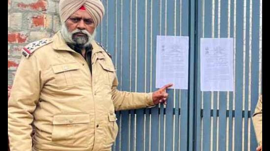 A cop shows the attachment notice in Latala village of Ludhiana on Sunday. (HT Photo)