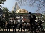 People look at a screen displaying the Sensex results on the facade of the Bombay Stock Exchange (BSE) building in Mumbai.