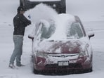 A person dusts snow off of a car during a winter storm, Sunday, Jan. 5, 2025, in Cincinnati. About 63 million people in the central and southern US are on alert for a 'heaviest' possible winterstorm.