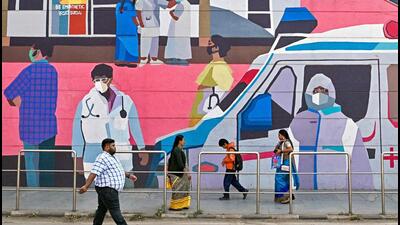 Pedestrians walk past a wall mural promoting awareness on using face masks, in Bengaluru on Monday. (AFP) Pedestrians walk past a wall mural promoting awareness on using face masks, in Bengaluru on Monday. (AFP)