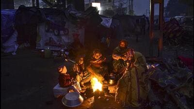 People sit around a bonfire to warm themselves on a cold winter evening in Jalandhar on Tuesday. (PTI)