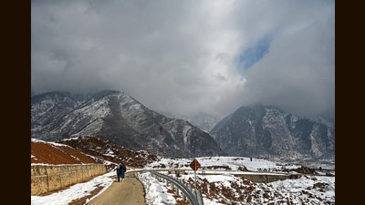 People walking in backdrop of snow covered hills in the outskirts of Srinagar on Tuesday. (Waseem Andrabi /HT) People walking in backdrop of snow covered hills in the outskirts of Srinagar on Tuesday. (Waseem Andrabi /HT)