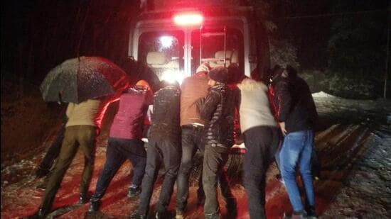 Rescuers pushing one of the stranded vehicles to safety on the Larot-Chanshal-Dodra Kwar road in Shimla district on Monday night. (HT Photo)