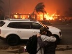 People embrace as they evacuate following powerful winds fueling devastating wildfires in the Los Angeles area, at the Eaton Fire in Altadena, California,
