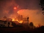 A helicopter performs a water drop, as smoke and flames rise from the Sunset Fire in the hills overlooking the Hollywood neighborhood of Los Angeles, California, US January 8, 2025. 