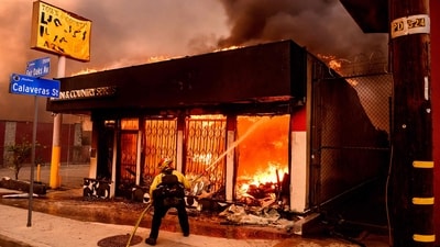 A firefighter douses flames as a liquor store burns during the Eaton fire in the Altadena area of Los Angeles. The out-of-control Palisades fire, which has burned more than 2,900 acres, is blazing through nearly five football fields per minute. (AFP) A firefighter douses flames as a liquor store burns during the Eaton fire in the Altadena area of Los Angeles. The out-of-control Palisades fire, which has burned more than 2,900 acres, is blazing through nearly five football fields per minute. (AFP)