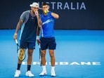 Serbia's Novak Djokovic (R) speaks with Australia's Nick Kyrgios before a point during a men's doubles match.