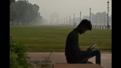 A man looks at his mobile phone as he sits along a road in front of the India Gate amid heavy smoggy conditions in New Delhi on November 7, 2024. (Photo by Money SHARMA / AFP) (AFP) A man looks at his mobile phone as he sits along a road in front of the India Gate amid heavy smoggy conditions in New Delhi on November 7, 2024. (Photo by Money SHARMA / AFP) (AFP)