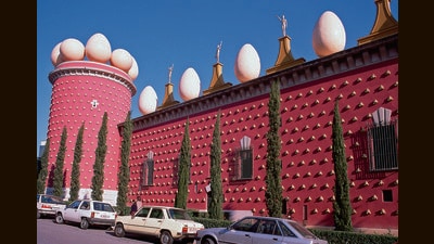 The museum is housed in a crimson building studded with pa de crostons (a local Catalan bread that Dali loved) made of yellow concrete, and topped with giant, white concrete eggs. (Getty Images) The museum is housed in a crimson building studded with pa de crostons (a local Catalan bread that Dali loved) made of yellow concrete, and topped with giant, white concrete eggs. (Getty Images)