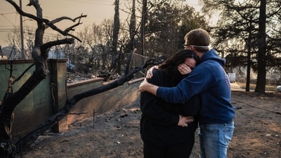 A man comforts his daughter amidst the charred ruins of their family home destroyed by the Eaton Fire in Altadena, California, on January 9, 2025. The massive wildfires, which have devastated neighborhoods and displaced thousands in Los Angeles, remained entirely uncontained as of January 9. US National Guard troops prepared to step in to help restore order, while large swaths of the city lay in ruins under a blanket of smoke and the pervasive smell of ash. (AFP) A man comforts his daughter amidst the charred ruins of their family home destroyed by the Eaton Fire in Altadena, California, on January 9, 2025. The massive wildfires, which have devastated neighborhoods and displaced thousands in Los Angeles, remained entirely uncontained as of January 9. US National Guard troops prepared to step in to help restore order, while large swaths of the city lay in ruins under a blanket of smoke and the pervasive smell of ash. (AFP)