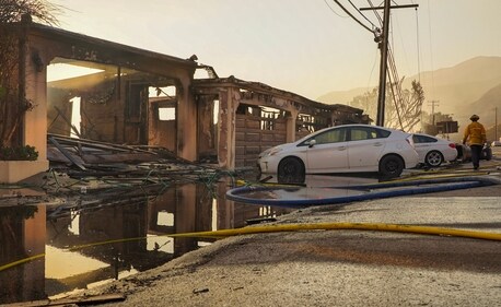 Firefighters work with water hoses near houses burned down in the Palisades Fire along the Pacific Coast Highway in Malibu, California, January 9, 2025. (AFP)