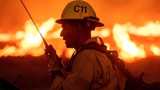 A firefighter communicates in front of the advancing Kenneth Fire in the West Hills section of Los Angeles.&nbsp;(AP Photo/Ethan Swope)