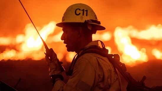A firefighter communicates in front of the advancing Kenneth Fire in the West Hills section of Los Angeles.&nbsp;(AP Photo/Ethan Swope)