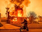 A motorcyclist stops to look at a burning home during the Eaton fire in the Altadena area of Los Angeles county. A motorcyclist stops to look at a burning home during the Eaton fire in the Altadena area of Los Angeles county.