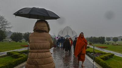 Visitors enjoy the cold and rain at the Lotus Temple in New Delhi Saturday evening. (RAJ K RAJ /HT PHOTO) Visitors enjoy the cold and rain at the Lotus Temple in New Delhi Saturday evening. (RAJ K RAJ /HT PHOTO)