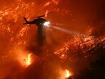 A fire fighting helicopter drops water as the Palisades fire grows near the Mandeville Canyon neighborhood and Encino, California, on January 11, 2025. A fire fighting helicopter drops water as the Palisades fire grows near the Mandeville Canyon neighborhood and Encino, California, on January 11, 2025.