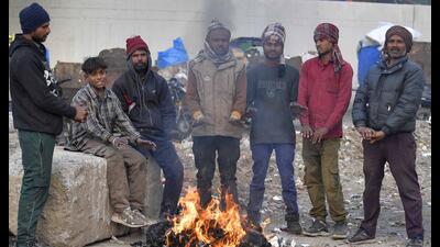 People gather near a bonfire to keep themselves warm after mercury dipped in Ludhiana on Sunday. (HT Photo)