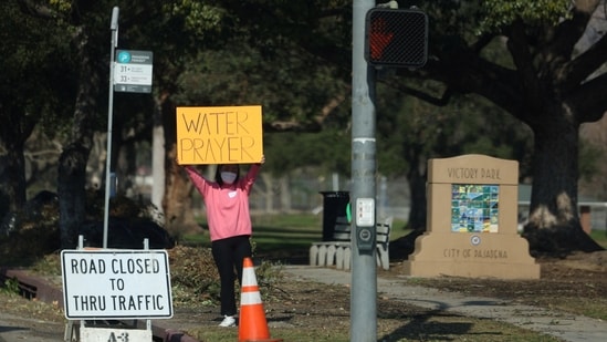 A person holds a sign asking for support for those affected by the Eaton Fire in Pasadena, California, U.S. Los Angeles County Sheriff Robert Luna warned residents against returning to their destroyed homes to salvage belongings, as the ash may contain dangerous materials like lead, arsenic, and asbestos.(REUTERS)