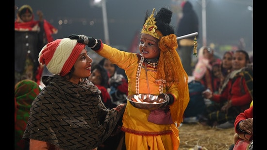 A kid dressed as Lord Krishna giving blessings to the pilgrims at the Sangam in Prayagraj on Monday. (Deepak Gupta/ht photo)