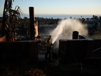 Apple Valley Fire District firefighter Wyatt Cortez hoses down hotspots at a home destroyed by the Palisades Fire in the Pacific Palisades neighborhood of Los Angeles, Monday, Jan. 13, 2025. (AP Photo/John Locher) Apple Valley Fire District firefighter Wyatt Cortez hoses down hotspots at a home destroyed by the Palisades Fire in the Pacific Palisades neighborhood of Los Angeles, Monday, Jan. 13, 2025. (AP Photo/John Locher)