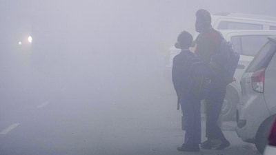 School students wait for transport amid dense morning fog in New Delhi on Wednesday (PTI) School students wait for transport amid dense morning fog in New Delhi on Wednesday (PTI)
