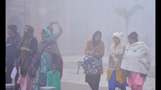 Visitors walk along the Heritage Street near the statue of Maharaja Ranjit Singh amid dense fog, in Amritsar on Thursday. (Sameer Sehgal/Hindustan Times)