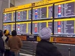Passengers look at the display board for information at the Delhi Airport after more than 100 flights were delayed as low visibility conditions due to dense fog impacted operations, in New Delhi on Friday.