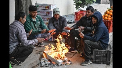 Fruit vendors sit around a fire to warm themselves on a cold winter day in Amritsar on Friday. (AFP)