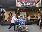 A man pushes a wheelchair-bound patient in front of posters and installations displayed to condemn the rape and murder of a doctor at the protest site inside the state-run RG Kar Medical College and Hospital in Kolkata on the eve of the court's verdict. (AFP)