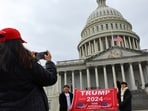A woman clicks a picture as people hold a placard in favour of US President-elect Donald Trump in front of the US Capitol building ahead of the presidential inauguration in Washington.