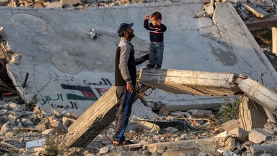 Under the deal, 33 hostages are set to be released over the next six weeks, in exchange for hundreds of Palestinians imprisoned by Israel. In pic: A man speaks with a boy standing on a broken concrete beam by the rubble of a collapsed building at a camp for people displaced by conflict in Bureij in the central Gaza Strip on January 17, 2025 (AFP) Under the deal, 33 hostages are set to be released over the next six weeks, in exchange for hundreds of Palestinians imprisoned by Israel. In pic: A man speaks with a boy standing on a broken concrete beam by the rubble of a collapsed building at a camp for people displaced by conflict in Bureij in the central Gaza Strip on January 17, 2025 (AFP)