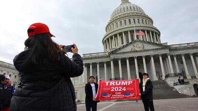 A woman clicks a picture as people hold a placard in favour of US President-elect Donald Trump in front of the US Capitol building ahead of the presidential inauguration in Washington. (REUTERS)