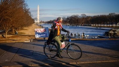A person riding a bicycle with a sign gestures on the day of the "People's March on Washington" ahead of the presidential inauguration of U.S. President-elect Donald Trump, in Washington. (REUTERS)