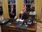 US President Donald Trump signs documents as he issues executive orders in the Oval Office at the White House on Inauguration Day in Washington.