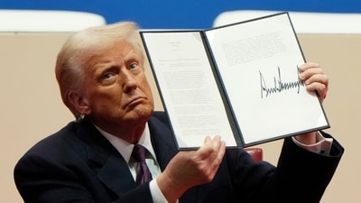 President Donald Trump holds up an executive order after signing it at an indoor Presidential Inauguration parade event in Washington, Monday. (AP) President Donald Trump holds up an executive order after signing it at an indoor Presidential Inauguration parade event in Washington, Monday. (AP)