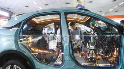 A guest at the exhibit looks into the inside of a car which has all its wires and inner workings exposed as part of a display at the expo (Amit Sharma)