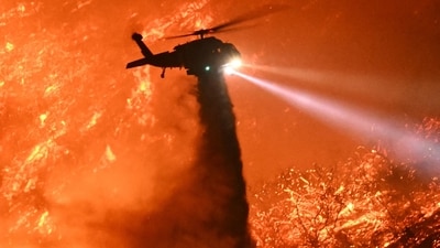 A fire fighting helicopter drops water as the Palisades fire grows near the Mandeville Canyon neighborhood and Encino, California, on January 11, 2025. (AFP) A fire fighting helicopter drops water as the Palisades fire grows near the Mandeville Canyon neighborhood and Encino, California, on January 11, 2025. (AFP)